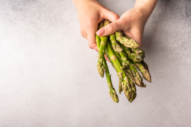 Women’s,Hands,Hold,A,Bunch,Of,Fresh,Green,Asparagus,Against