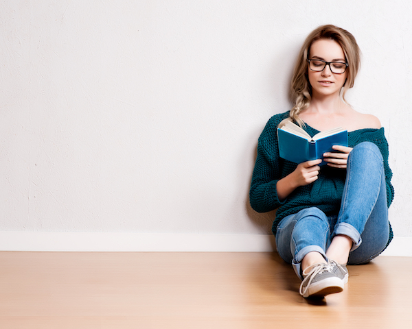 Young,Blonde,Woman,Relaxing,On,Floor,At,Home,Reading,Book.