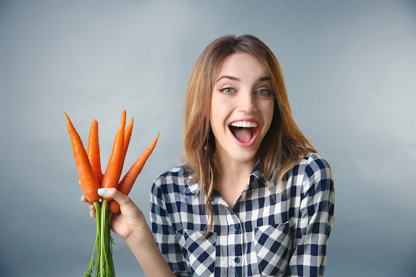 Beautiful,Girl,Eating,Carrot,On,Grey,Background