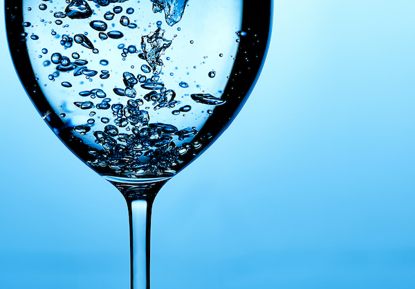 Pouring,Water,Into,A,Glass,Against,Light,Blue,Background.,Fresh