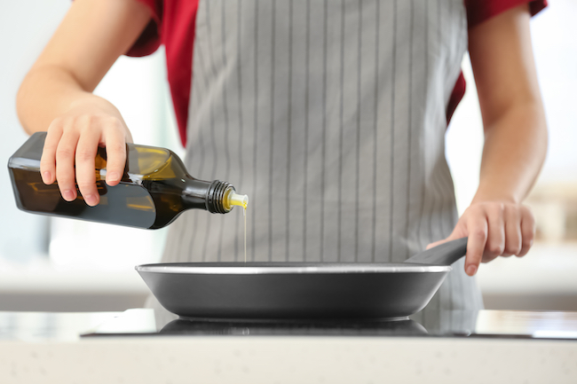 Woman,Pouring,Cooking,Oil,From,Bottle,Into,Frying,Pan,On