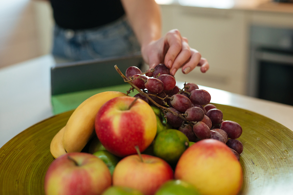 Cropped image of woman eating fruits on kitchen
