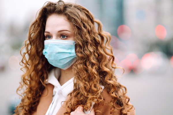 Woman in protective medical mask on her face on the street. Woman, wear face mask. Corona virus.