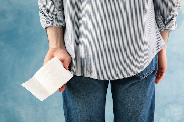 Man holds toilet paper on blue background, close up