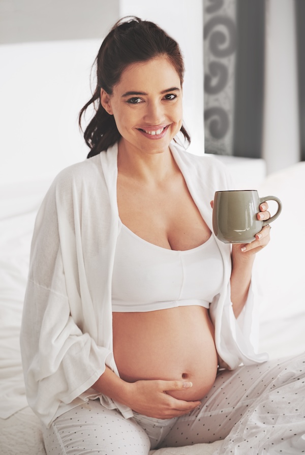 Oh that glow. Shot of a pregnant woman relaxing with a beverage at home