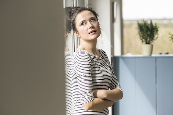 Serious woman looking out of window at home