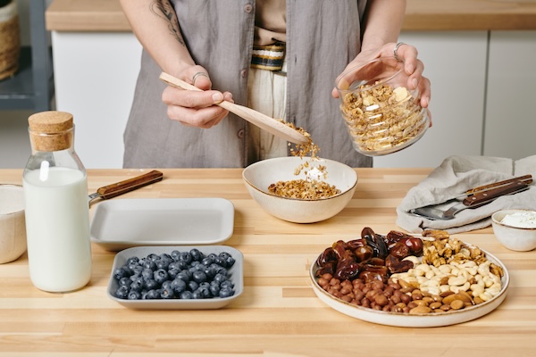 Hands of female putting muesli into bowl