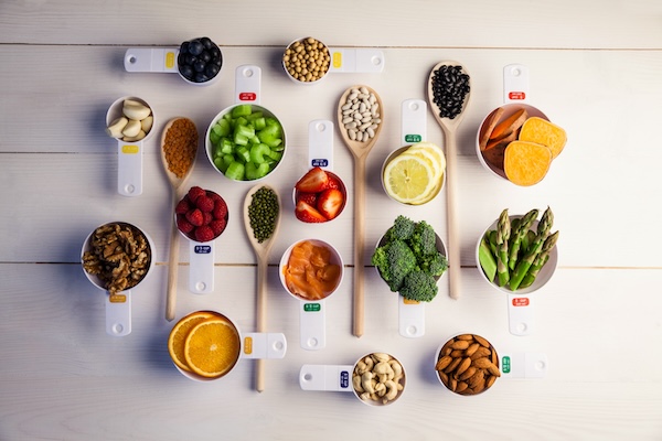 Portion cups and spoons of healthy ingredients on wooden table