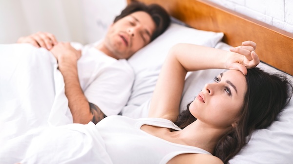 Woman Lying in Bed While Partner Sleeps and Snores