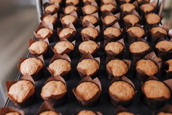 close up view of woman holding holding rack of croissants in a bakery.