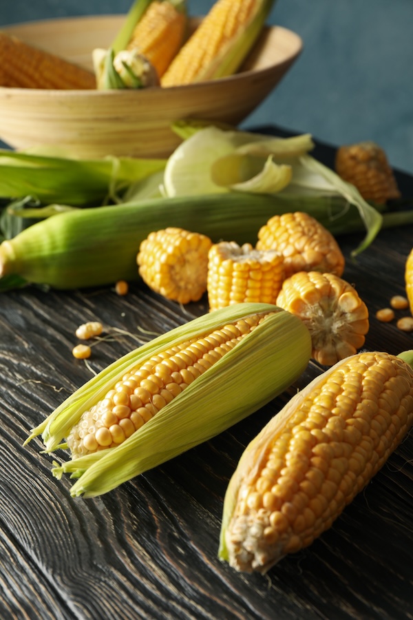 Composition with fresh raw corn on wooden table