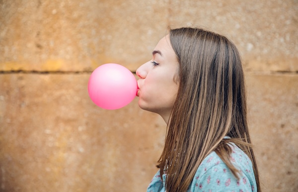 Young teenage girl blowing pink bubble gum