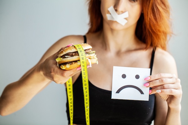 Diet. Portrait woman wants to eat a Burger but stuck skochem mouth, the concept of diet, junk food, willpower in nutrition.