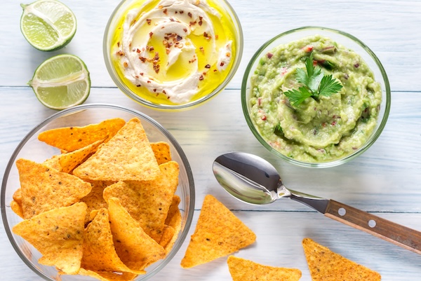 Bowls of hummus and guacamole with tortilla chips