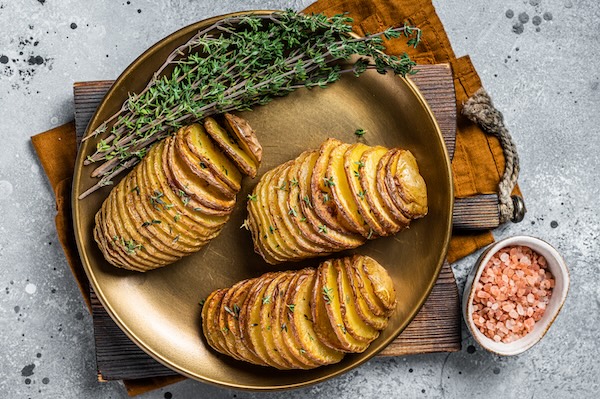 Baked Hasselback Potato with Fresh thyme and rosemary. Gray background. Top view