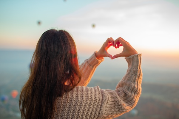 Happy woman during sunrise watching hot air balloons in Cappadocia, Turkey